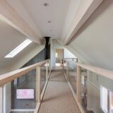 Open house landing with glass balustrade and vaulted ceiling at first floor